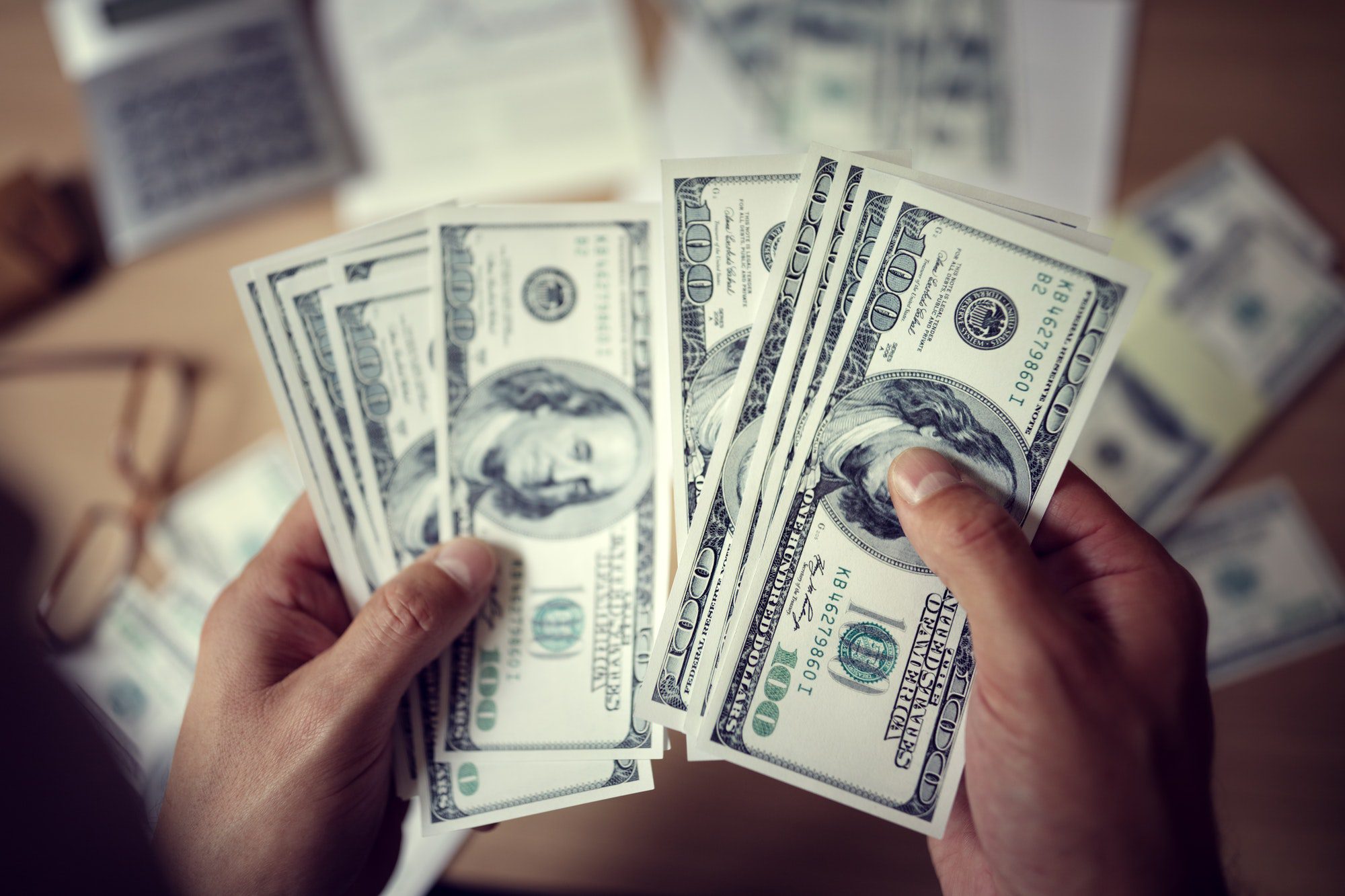Business man counting money to decide cost between Medicare Advantage and Original Medicare.