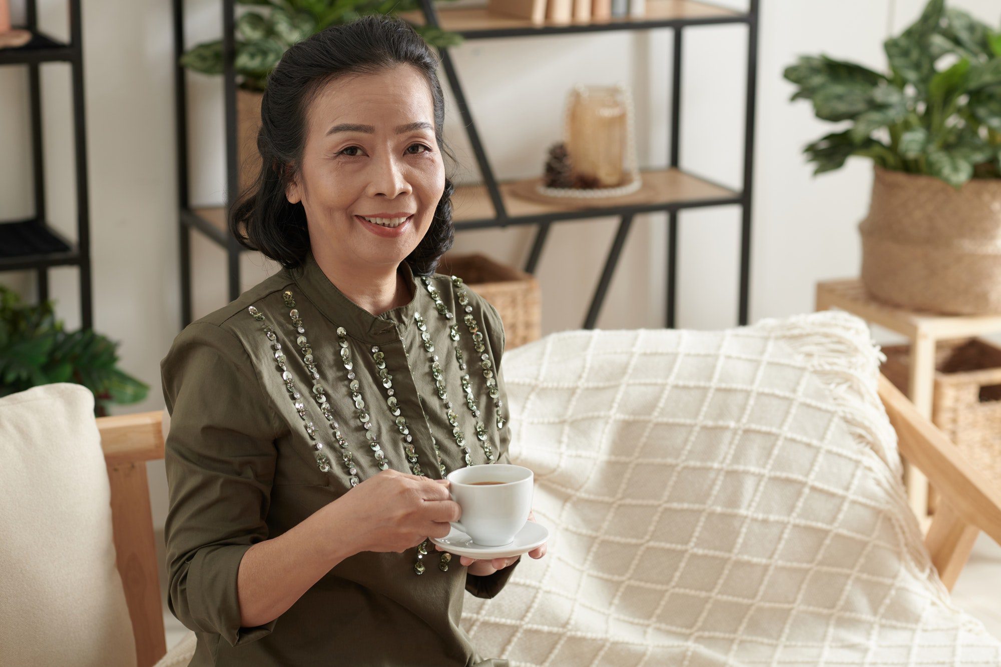 Elegant Senior Woman enjoying a cup of tea as she researches why the new Alzheimers drug is making her medicare premiums are going up.
