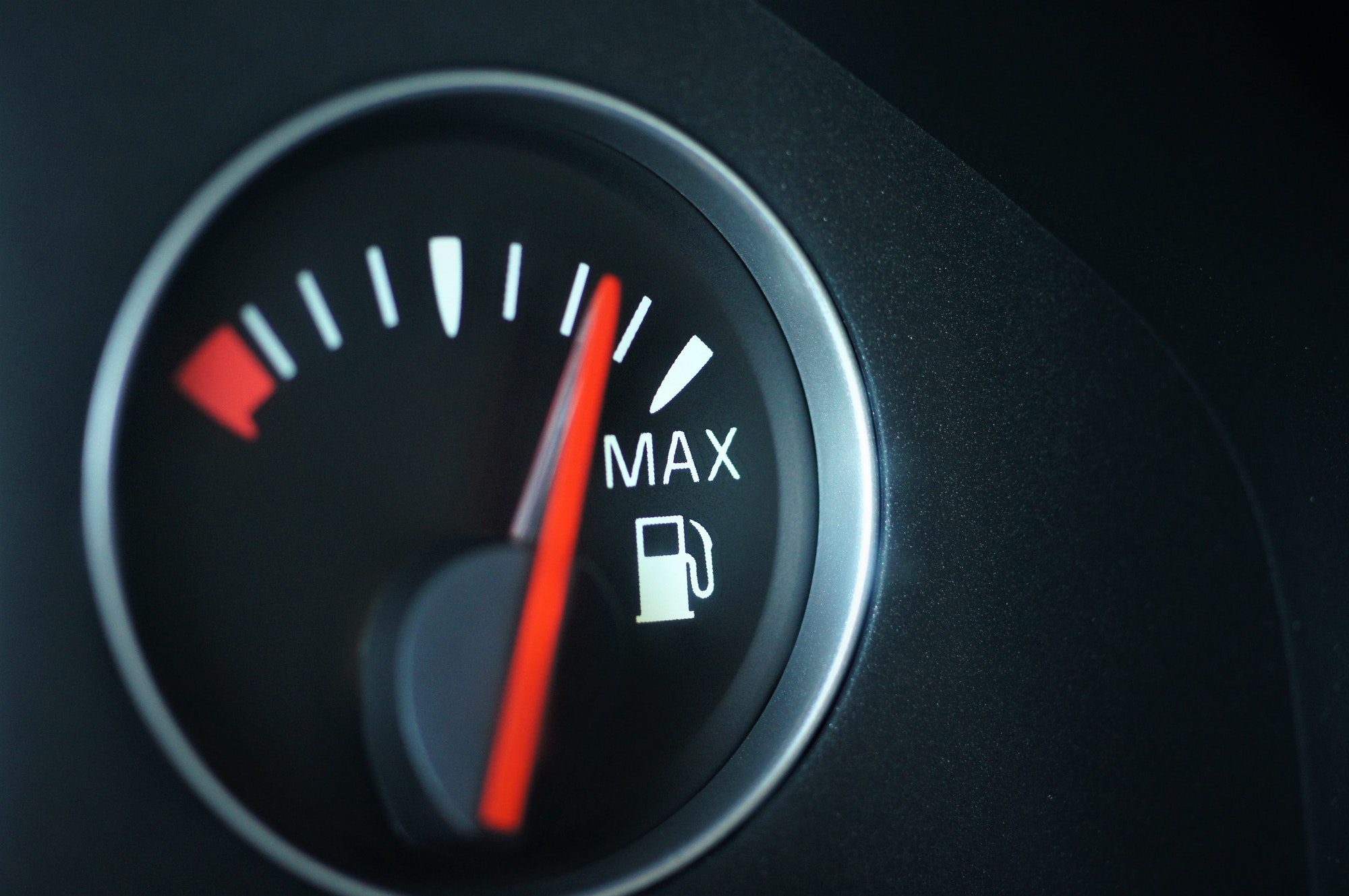 Closeup of car fuel gauge on black background representing social security maximizations.