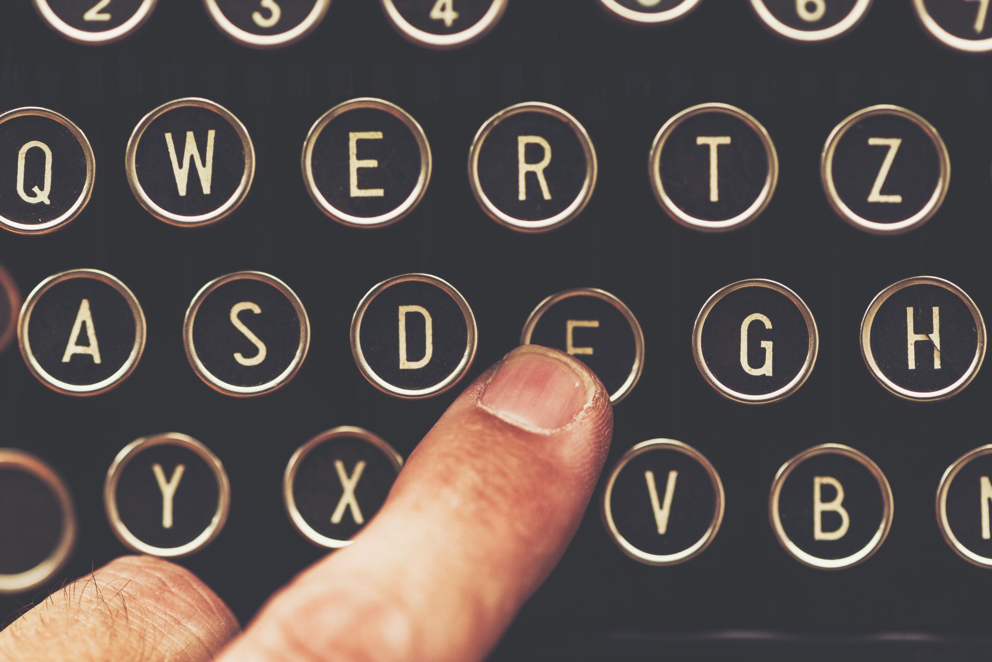 Finger on vintage typewriter machine pointing to the letter F