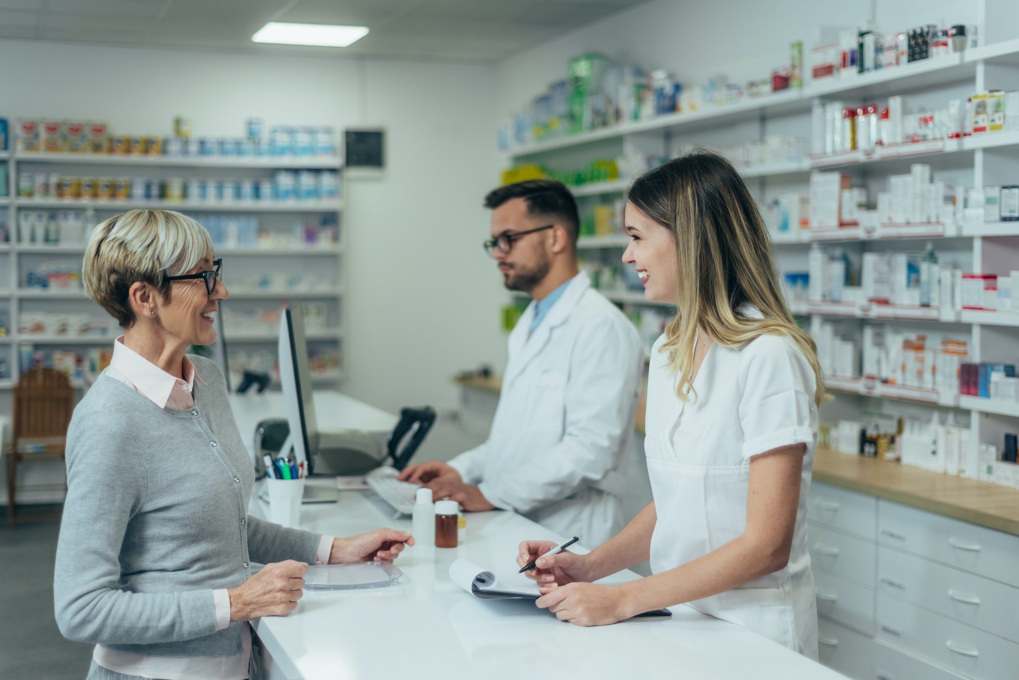 Pharmacist giving prescription medications to smiling senior female customer