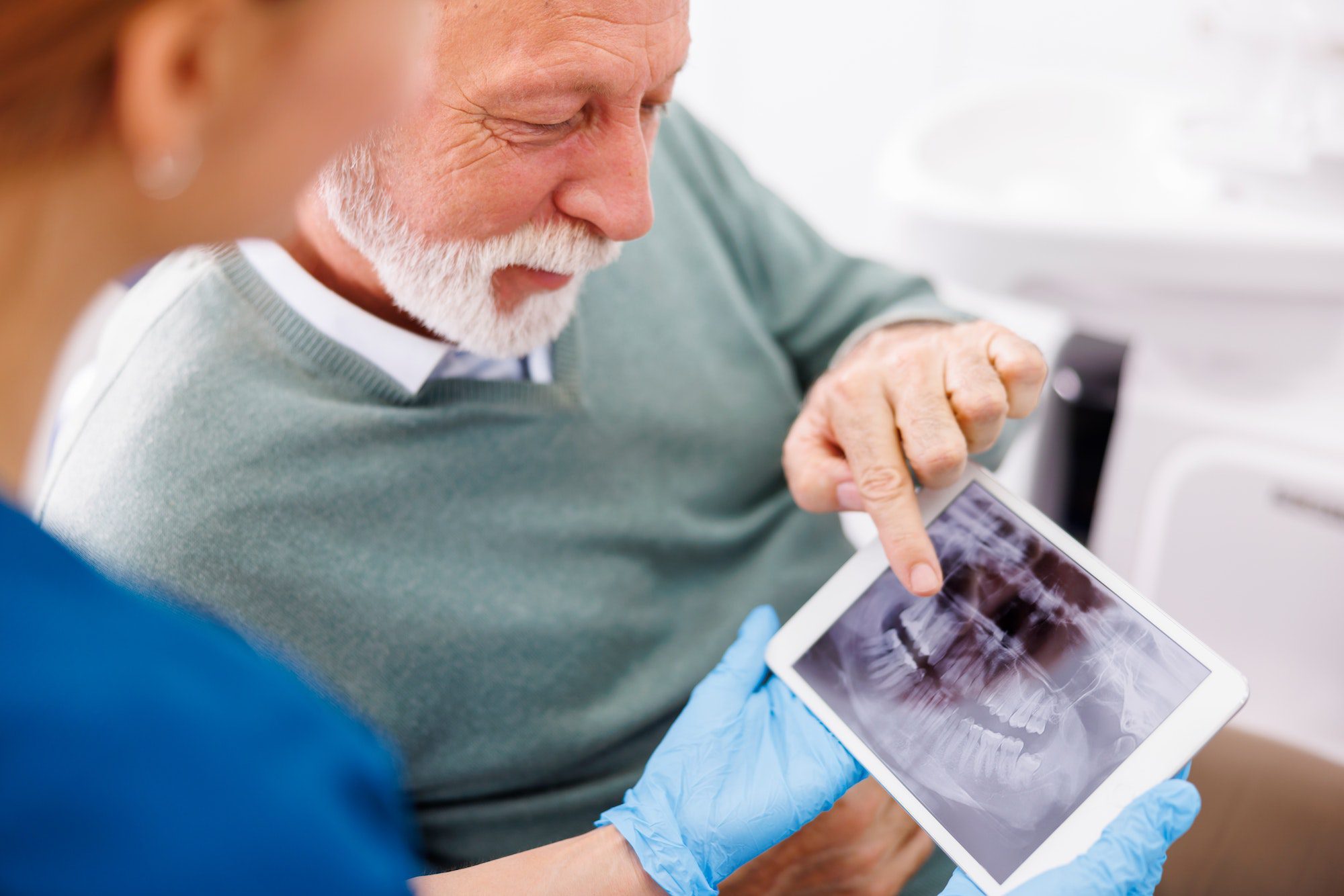 Senior man consulting with dentist at dental clinic with Medicare Dental, Vision, and Hearing Care