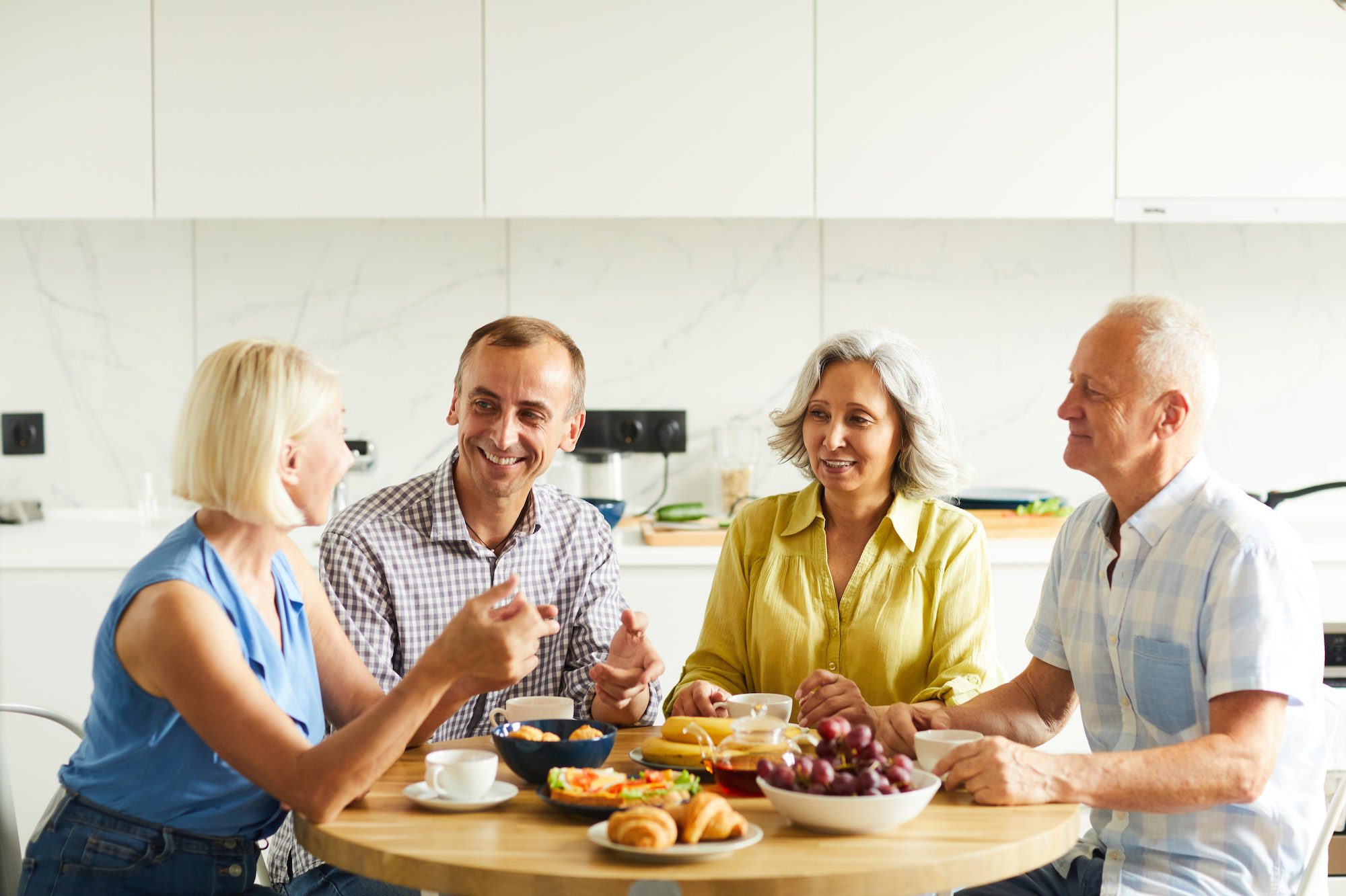 Mature Friends Gathered at Kitchen Table with new 2023 Medicare Premiums